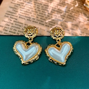 Detail of vintage hollow flower gold heart earrings with white pearl resin inlays