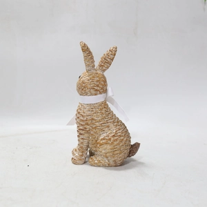 Close-up of resin rabbit statue with woven rattan texture and white silk bow detail