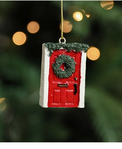 Close-up of a red resin Christmas door hanging ornament with green wreath on a tree