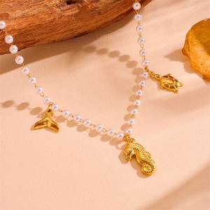 Détail du collier de perles avec pendentifs dorés hippocampe, tortue et queue de baleine