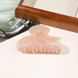 Macro detail of iridescent pearly pink resin hair claw clip with a glossy finish