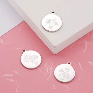 Detailed close-up of silver stainless steel round pendants with engraved floral patterns