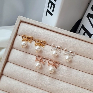 Vue détaillée des boucles d'oreilles nœud en argent 925 avec perles dorées et rosées