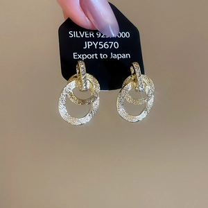 Dettaglio di orecchini a cerchio intrecciati placcati oro 18k con pavé di zirconi