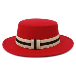 Detail of red wool felt boater hat featuring minimalist beige and black ribbon band