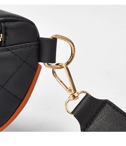 Detailed close-up of golden metal lobster clasp and orange edge stitching on black leather