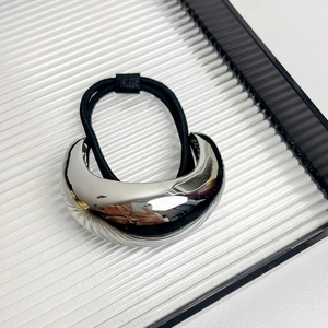 Close-up of a sleek silver arched metal hair tie on a minimalist white textured background