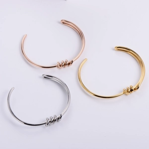 Minimalist knot cuff bracelets in gold, silver, and rose gold finishes on white background
