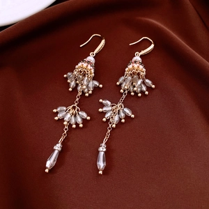 Detail of ethnic tassel earrings featuring glass beads and golden drop pendant chains