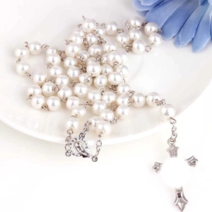 Chapelet élégant avec perles blanches et pendentif croix en argent sur une assiette blanche