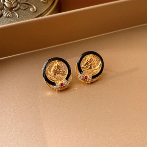Detailed close-up of vintage gold horse head relief earrings with black enamel and red gemstone