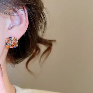 Detailed close-up of vibrant square zirconia stud earrings on a model's ear
