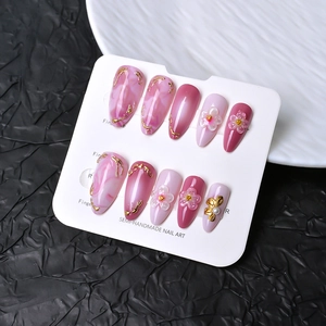 Semi-handmade almond press-on nails with pink gradient, 3D floral accents, and gold edges