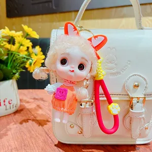 Cute cartoon doll keychain with orange fox ears and red lanyard hanging on a white bag