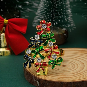 Detail of a gold Christmas tree napkin ring with colorful crystals on a wooden tray