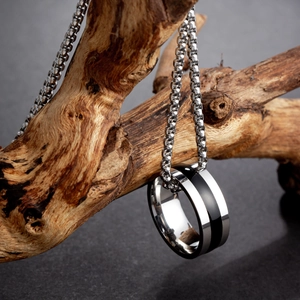 Polished silver and black ring pendant necklace displayed on a piece of natural driftwood