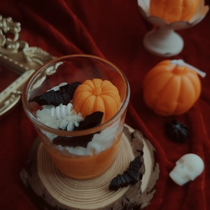 Top view of Halloween candle with pumpkin and bat decorations on velvet background