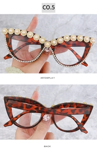 Dettaglio occhiali da sole cat-eye tartarugati con fiori dorati e decori in strass