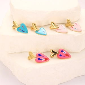 Detail of colorful enamel heart earrings on stone stand in blue, light pink and rose red