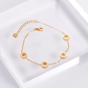 Detailed close-up of gold chain bracelet with Roman numeral charms and white zircons