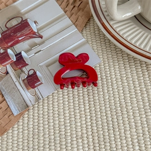 Detail of a small red heart hair claw clip with gold engraving on a stylish card