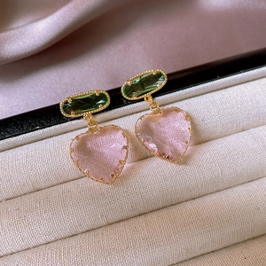 Detail von herzförmigen Zirkon-Ohrringen in Pink und Grün mit eleganter Vergoldung