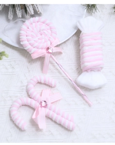 Pink and white plush Christmas candy ornaments with bow detail on white knit background