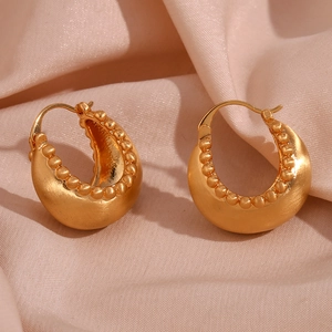 Detail of 18K gold-plated crescent earrings with matte brushed finish and beaded edge