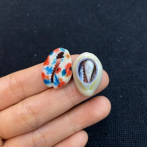 Hand holding natural printed sea shells with colorful patterns for DIY jewelry making
