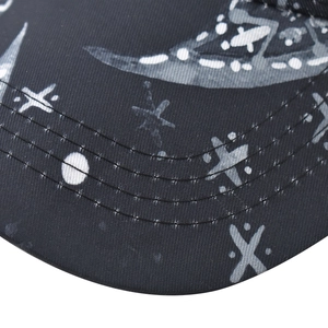 Close-up of black cotton baseball cap brim with white star and moon print details