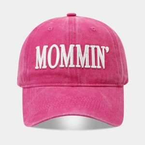 Close-up of MOMMIN embroidered text on washed cotton pink baseball cap with premium stitching