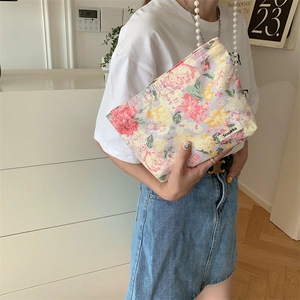 Floral cotton makeup bag with brand tag held by a model in a cozy home setting