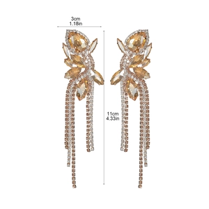 Close-up of sparkling amber glass rhinestone bow earrings with long tassel fringes