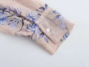Détail du poignet en mousseline avec imprimé floral bleu et fermeture à bouton blanc