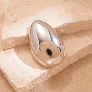Macro detail of metallic silver teardrop brooch with smooth mirror finish on stone
