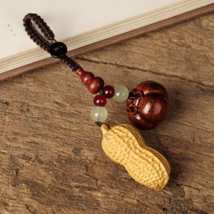 Handcrafted wooden key ring with peanut and pumpkin charms on a rustic wood background