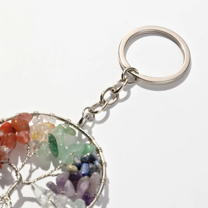 Detailed view of Tree of Life keychain with natural colorful crystal stones on white background