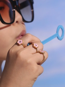 Detailopname van kind met gouden ringen, roze bloemen en kristallen met bellenblazer