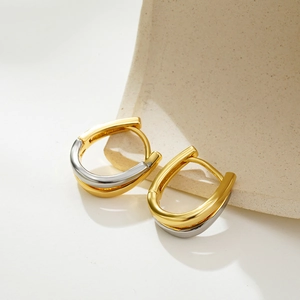 Macro shot of polished U-shaped earrings featuring two-tone gold and silver plating