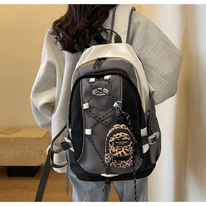 Close-up of a color-block backpack with leopard print mini pouch and bungee cord details