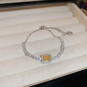 Macro detail of rectangle yellow crystal bracelet with cubic zirconia in a white velvet box