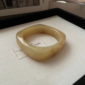 Macro shot of square amber resin bracelet with natural marble texture on beige linen