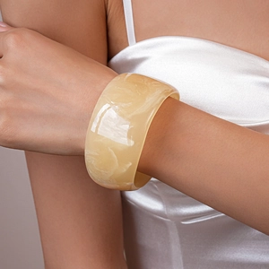 Detailed view of resin bangle with amber marble texture worn with white dress