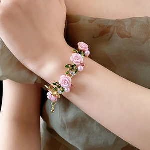 Détail du bracelet rose avec feuilles vertes et perles porté par un mannequin