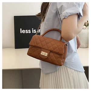 Detail of brown quilted leather bag featuring a gold chain strap and metal lock clasp