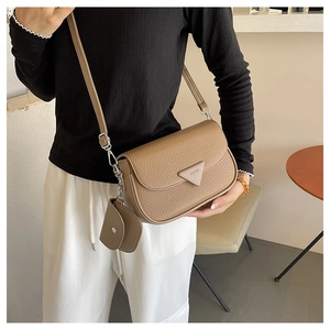 Détail d'un sac à bandoulière en cuir marron grainé avec un mini porte-monnaie amovible