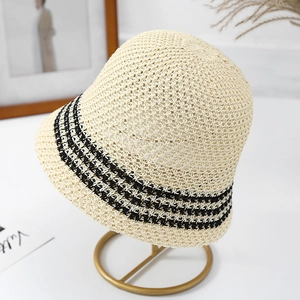 Close-up of beige hollow knit bucket hat with black stripes on a metal display stand