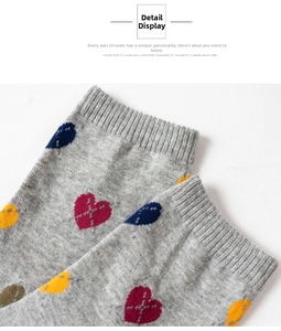 Detailed macro view of gray knitted socks featuring multi-color heart jacquard and ribbed cuffs