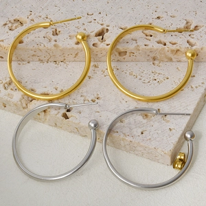 Flat lay of gold and silver 304 stainless steel C-shaped hoop earrings on beige stone