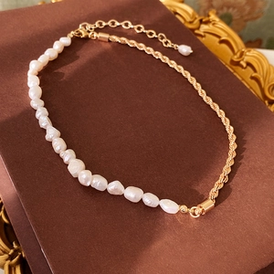 Détail du bracelet en perles d'eau douce et chaîne torsadée dorée sur fond vintage